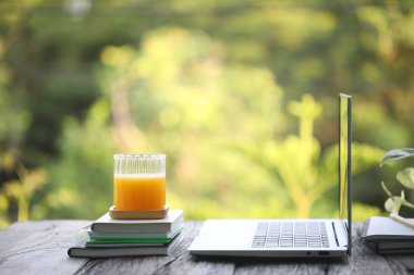 Dizüstü bilgisayar manzarası, cam bardak ve defterlerde mango suyu.