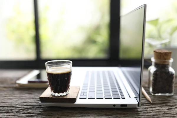 Laptop side view and coffee glass cup on wooden table indoor