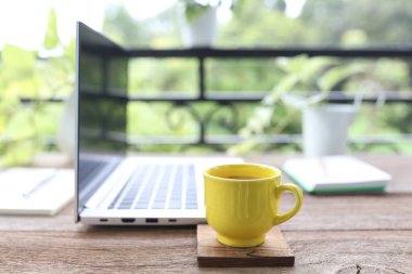 Sarı kahve fincanı, dizüstü bilgisayar yan görüntüsü.