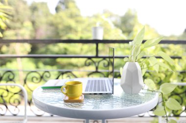 Dizüstü bilgisayar ve cam masanın üzerindeki sarı kahve fincanı.