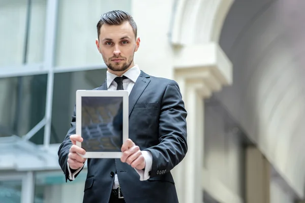 Businessman shows the tablet in camera