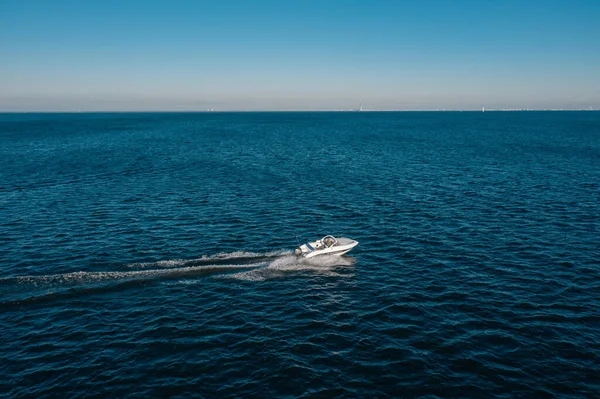 Una vista desde una altura de una lancha blanca navegando en el mar de abedul. La lancha deja una marca en el agua. El concepto de viaje por el agua y la recreación. — Foto de Stock