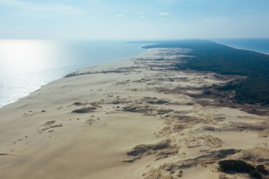 Curonian Gölünü Baltık Denizi 'nden ayıran dar ve uzun kumlu kılıç şeklinde bir kara şeridi manzarası. Curonian Tükürüğünün gri kum tepeleri.