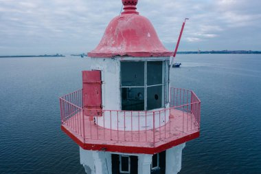 Finlandiya Körfezi 'nin ortasındaki küçük bir adada deniz feneri, Kronstadt kaleleri, durakta bir kargo tankeri, bir çim yolu. Havadan yakın çekim görüntüsü