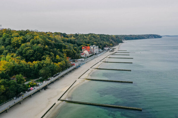 Panoramic aerial view of the Baltic Sea coast and the promenade in the resort town of Svetlogorsk, beach, Waves breaking on breakwaters, Old wooden ridges. Kaliningrad region