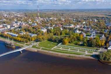 Veliky Novgorod 'daki Gostiny Dvor Arcade' nin panoramik hava manzarası, güneşli bir günde sonbahar ağaçlarının tepeleri. Ortaçağ pazarının kalıntıları. Volkhov nehri üzerindeki büyük köprü.