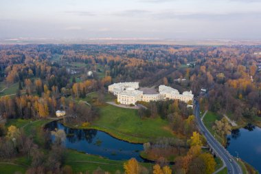 Pavlovsk Parkı ve Pavlovsk Sarayı 'nın sonbahar akşamları panoramik hava manzarası. Parlak sonbahar manzarası, Slavyanka nehri. St. Petersburg 'un bir banliyösü