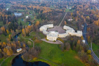 Pavlovsk Parkı ve Pavlovsk Sarayı 'nın sonbahar akşamları panoramik hava manzarası. Parlak sonbahar manzarası, Slavyanka nehri, Centaur köprüsü. St. Petersburg 'un bir banliyösü