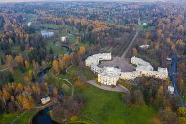 Pavlovsk Parkı ve Pavlovsk Sarayı 'nın sonbahar akşamları panoramik hava manzarası. Parlak sonbahar manzarası, Slavyanka nehri, Centaur köprüsü. St. Petersburg 'un bir banliyösü