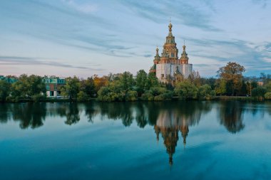 Olga 'nın Göleti ve Peterhof' ta gün batımında Peter ve Paul Katedrali, gökyüzünün yansıması ve sudaki ağaçlar, kubbeli bir kilise, kartpostal için bir fotoğraf..
