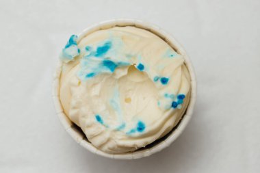 Beyaz bir masada karton bir sepetin içinde kemirilmiş ya da bozulmuş bir kremalı pasta. Pişirme ve şekerleme konsepti.