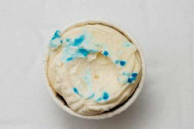 Beyaz bir masada karton bir sepetin içinde kemirilmiş ya da bozulmuş bir kremalı pasta. Pişirme ve şekerleme konsepti.