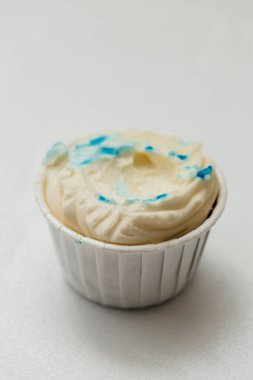 Beyaz bir masada karton bir sepetin içinde kemirilmiş ya da bozulmuş bir kremalı pasta. Pişirme ve şekerleme konsepti.