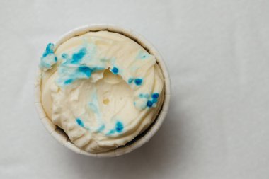 Beyaz bir masada karton bir sepetin içinde kemirilmiş ya da bozulmuş bir kremalı pasta. Pişirme ve şekerleme konsepti.