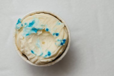 Beyaz bir masada karton bir sepetin içinde kemirilmiş ya da bozulmuş bir kremalı pasta. Pişirme ve şekerleme konsepti.