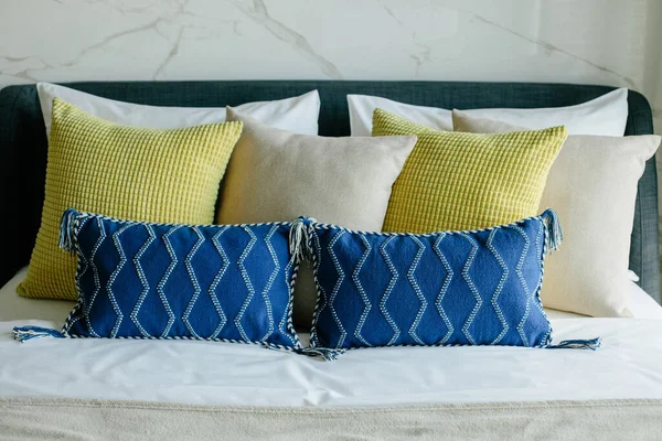 Yatakta farklı renk ve boyutlarda yastıklar düzgünce dizilmiş. İç tasarım..