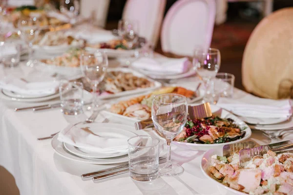 餐桌上摆设宴会或庆祝活动用的餐桌 酒类饮料 葡萄酒和果汁的空杯子 固定的餐桌 白盘上的纸巾和桌上的餐具 冷开胃菜和沙拉 — 图库照片