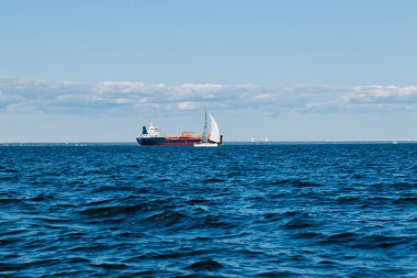 Bir yaz günü Finlandiya Körfezi 'nin sularından bakıldığında, uzaklarda kargo gemileri ve yatlar, mavi sular ve büyük dalgalar görülür. St. Petersburg kıyıları. Rusya, Peterhof, 31.07.2021