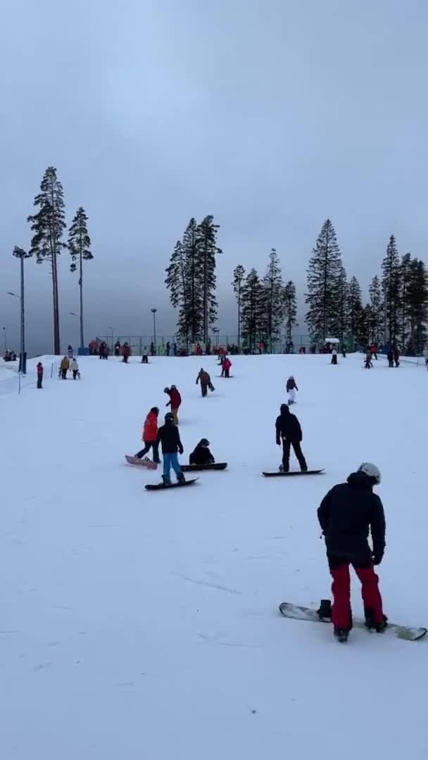 La pista de esquí en la estación de Igora, esquiadores y snowboarders se deslizan por la ladera nevada de invierno de la montaña. Rusia, San Petersburgo, 2 de enero de 2022 — Vídeo de stock