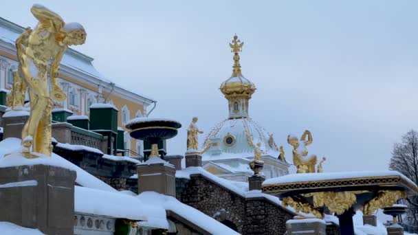 Esculturas doradas cubiertas de nieve en el fondo del gran palacio, una cúpula dorada con un águila de doble cabeza, jarrones de mármol y cuencos — Vídeo de stock