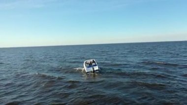 Finlandiya Körfezi 'nin sularında yüzen yüksek hızlı beyaz zevk teknesinin havadan görüntüsü. Denizdeki bir tekneden gelen büyük dalgalar. Motorlu tekneden köpük izi kalmış..