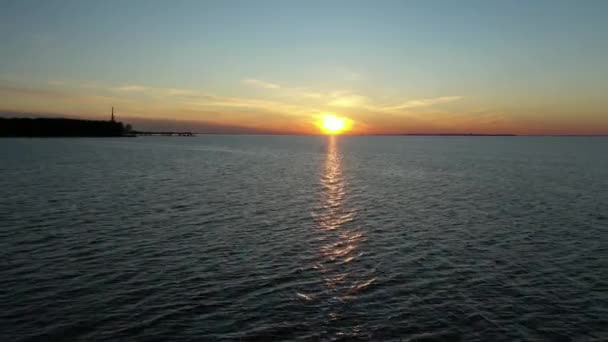 Αεροφωτογραφία ενός drone που πετά πάνω από την επιφάνεια της θάλασσας ή του ωκεανού το ηλιοβασίλεμα, η αντανάκλαση του πορτοκαλί ήλιου στο νερό.Κύματα και φως με λάμψη στην επιφάνεια του νερού.Ουράνιο φόντο — Αρχείο Βίντεο