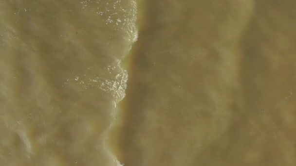 위에서 아래까지 공중에서 내려다본 발트해의 파도는 하얀 모래, 강한 바람, 물결, 얕은 물 이 있는 아름다운 모래사장으로 부드럽게 굴러 간다. — 비디오