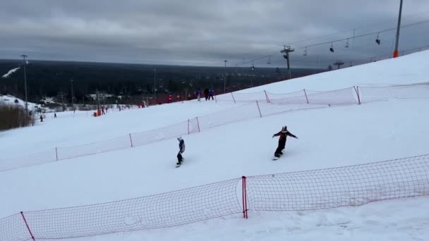 Stok narciarski w ośrodku Igora, narciarze i snowboardziści zjeżdżają ze śnieżnego zimowego zbocza góry. Kolejka linowa, wyciąg narciarski. Rosja, Sankt Petersburg, 2 stycznia 2022 — Wideo stockowe