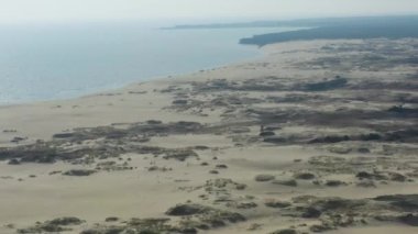 Curonian Gölünü Baltık Denizi 'nden ayıran dar ve uzun kumlu kılıç şeklinde bir kara şeridi manzarası. Curonian Tükürüğünün gri kum tepeleri