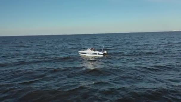 Letecký pohled na vysokorychlostní bílý rekreační člun plující vodou Finského zálivu. Velké vlny z lodi v moři. Z motorového člunu zbyla pěnová stopa. — Stock video