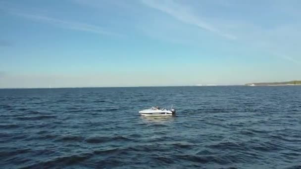 Flygfoto över en snabbgående vit fritidsbåt som seglar genom Finska vikens vatten. Stora vågor från en båt i havet. Ett skumspår återstår från motorbåten. — Stockvideo