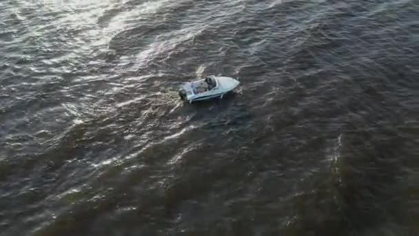 Flygbilder av en snabbgående vit fritidsbåt som seglar i Finska vikens vatten. Stora vågor från båten i havet. Det finns ett skumspår från motorbåten — Stockvideo