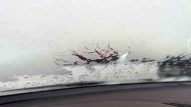 Arabanın içine, donmuş ön cama bak. Arabanın camında eriyen buz. Eriyen karın dokusu yakın plan, ön camda kış desenleri.