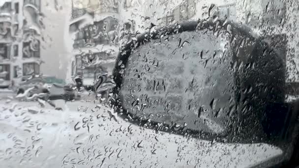 Σταγόνες νερού κατεβαίνουν το παράθυρο του αυτοκινήτου το χειμώνα. Το χιόνι λιώνει και στάζει στο παρμπρίζ. Πλευρικός καθρέφτης στο βάθος. Κοντινό πλάνο — Αρχείο Βίντεο