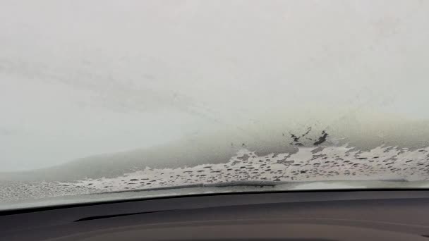 Pohled do auta na zamrzlé čelní sklo. Tající led na okně auta. Textura tání sněhu zblízka, Zimní vzory na čelním skle — Stock video