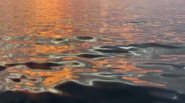 Soyut dalga arkaplanı ve günbatımı yansımaları suda. Denizde renkli gün batımı noktaları. Su yüzeyinin dalgaları, günbatımı ışığı