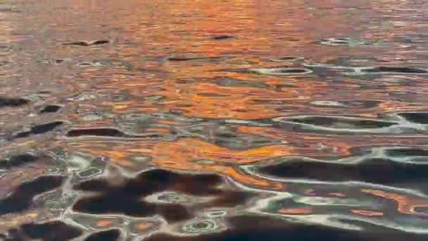 Fondo de ondas abstractas con reflejos al atardecer en el agua. Coloridos puntos de puesta de sol en el mar. Ondas de la superficie del agua, luz del atardecer — Vídeo de stock
