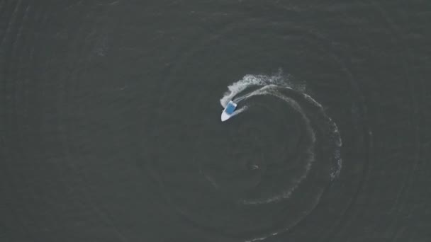 Letecký pohled na motorový člun s modrou střechou pohybující se v kruhu a vytvářející krásné tvary v moři. Koncept rekreace a cestování — Stock video