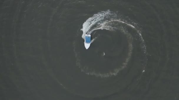 Vista aérea de una lancha rápida con un techo azul que va en círculo y crea hermosas formas en el mar. El concepto de recreación y viajes — Vídeos de Stock