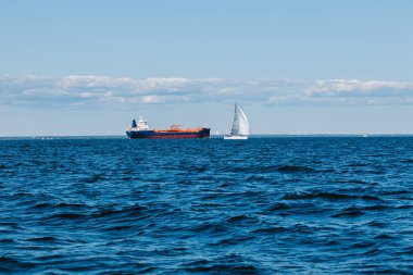 Bir yaz günü Finlandiya Körfezi 'nin sularından bakıldığında, uzaklarda kargo gemileri ve yatlar, mavi sular ve büyük dalgalar görülür. St. Petersburg kıyıları. Rusya, Peterhof, 31.07.2021