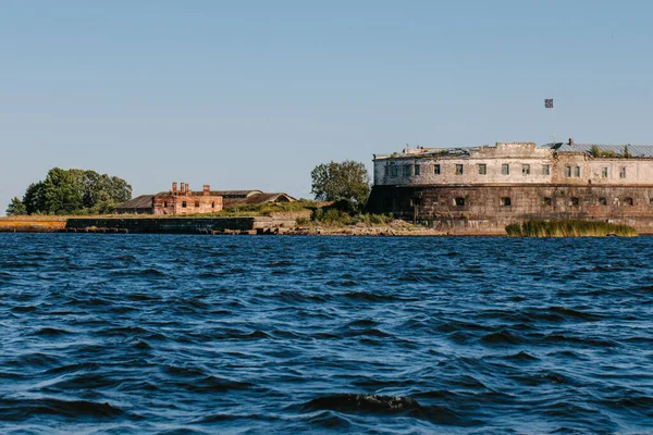 Vista dall'acqua del più antico forte Kronshlot e del faro a fascia bassa nelle acque del Golfo di Finlandia a Kronstadt, castello della corona, fortezza difensiva — Foto Stock