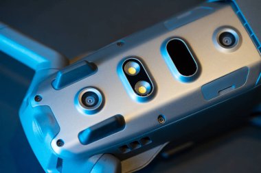 Mavi ışıkta siyah bir arkaplanda ters dönmüş bir Mavic 2 Pro quadcopter. Kızılötesi sensörler ve sensör sistemi, diyot lamba. Kopyalamak için boşluk.
