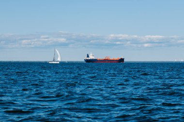 Bir yaz günü Finlandiya Körfezi 'nin sularından bakıldığında, uzaklarda kargo gemileri ve yatlar, mavi sular ve büyük dalgalar görülür. St. Petersburg kıyıları. Rusya, Peterhof, 31.07.2021