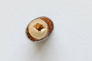 Kapağı olmayan cam bir kahve kavanozunun üst görüntüsü, altın renkli etiketi yırtılmış, ambalajın bütünlüğü kırılmış, arka plan. Yakın plan..