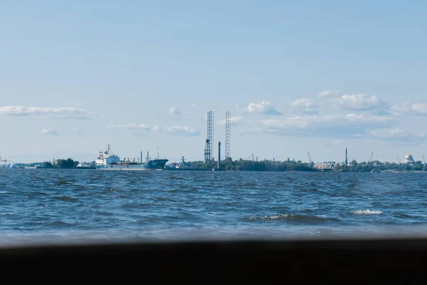 Blick vom Wasser auf die Küste Kronstadts, Frachtschiffe, Schwimmende Bohrplattform, Bohrkräne. Russland, Kronstadt, 31.07.2021 — Stockfoto