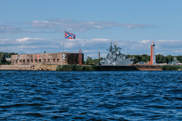 View from the water of the harbor and the parking of warships and submarines,the coastline of Kronstadt,the waters of the Gulf of Finland,the blue sea and waves.Russia,Kronstadt,31.07.2021