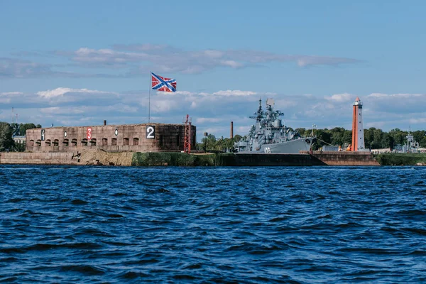 Blick vom Wasser auf den Hafen und das Parken von Kriegsschiffen und U-Booten, die Küste Kronstadts, die Gewässer des Finnischen Meerbusens, das blaue Meer und Wellen. Russland, Kronstadt, 31.07.2021 Stockfoto