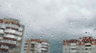 Büyük cam damlaları. Pencerenin dışında yağmur var. Bulutlar. Şehrin uyku alanı.