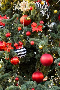 Güzel kırmızı ve altın toplar, Noel süslemeleri köknar dallarını süslüyor. Noel arkaplanı, kartpostal, ağaçtaki çelenkler ve kırmızı fiyonklar..