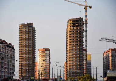 Tamamlanmamış yüksek binaları olan büyük endüstriyel vinçler. Çok katlı bir apartmanın inşaatı, ve şimdiden yakınlarda ikamet eden evler..